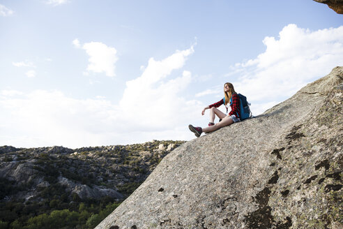 Spanien, Madrid, junge Frau ruht sich auf einem Felsen während eines Wandertages aus - ABZF02004