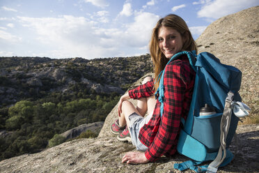 Spain, Madrid, smiling young woman resting on a rock during a trekking day - ABZF02005