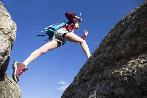 Spain, Madrid, young woman jumping between rocks during a trekking day - ABZF02006
