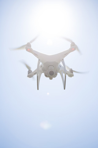 Fliegende Drohne mit Kamera bei Gegenlicht, lizenzfreies Stockfoto