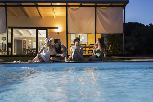 Vier Freunde entspannen sich in der Abenddämmerung am Pool - ZOCF00301