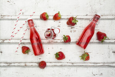 Three glass bottles of homemade strawberry lemonade and strawberries on white wood - LVF06105