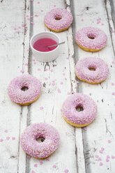 Sechs Krapfen mit rosa Zuckerguss und Zuckergranulat auf Holz - LVF06108