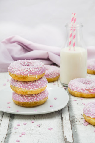 Doughnuts with pink icing and sugar granules and a bottle of milk stock photo