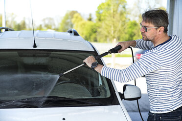 Mann beim Reinigen der Windschutzscheibe seines Autos - MAEF12201