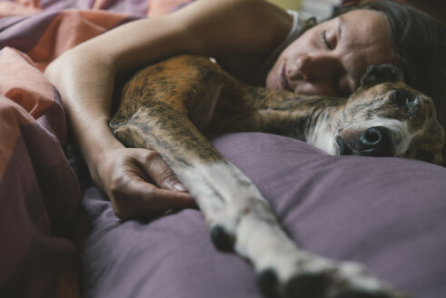 Woman lying in bed with her dog - SKCF00294