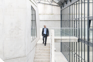 Mature busiinessman walking down stairs - FMKF04121