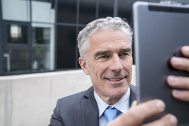 Mature businessman taking a smartphone selfie - FMKF04125