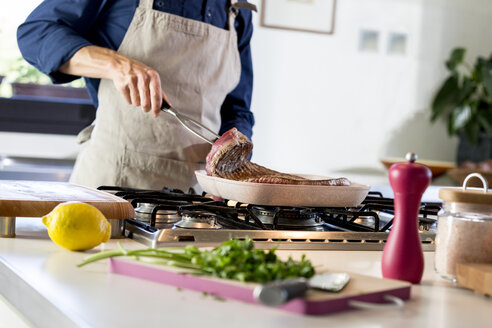 Junger Mann bei der Zubereitung von gegrilltem Teakholz zu Hause - ZOCF00316