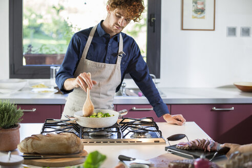 young man preparing broccoli in kitchen - ZOCF00322