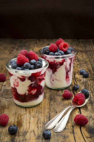 Two glasses of Greek yogurt with berry groats, fresh blueberries and raspberries on wood stock photo