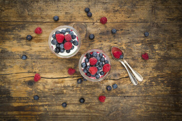 Two glasses of Greek yogurt with berry groats, fresh blueberries and raspberries on wood - LVF06116