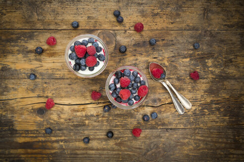 Zwei Gläser griechischer Joghurt mit Beerengrütze, frischen Heidelbeeren und Himbeeren auf Holz - LVF06116