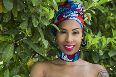 Porträt einer lächelnden jungen Frau mit Piercings und traditioneller brasilianischer Kopfbedeckung - ABZF02018