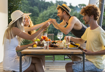 Glückliche Freunde beim Abendessen am Tisch im Freien - ZOCF00325