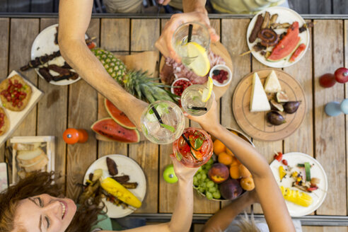 Friends clinking glasses above outdoor table - ZOCF00327