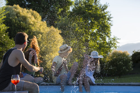 Four friends having fun at the pool edge in the garden - ZOCF00345