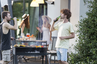 Two men having a beer at barbecue grill - ZOCF00355