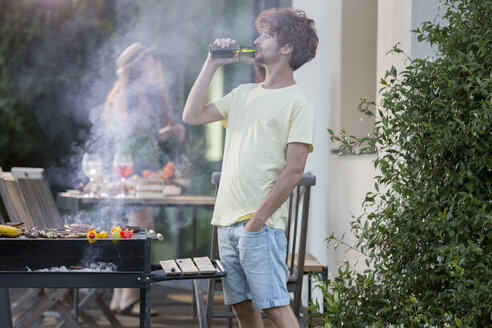 Mann trinkt ein Bier am Grill - ZOCF00356