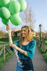 Porträt einer lachenden jungen Frau mit grünen Luftballons - DAPF00754