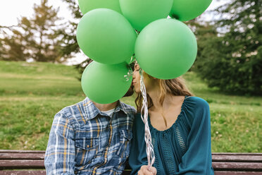 Junges Paar küsst sich hinter grünen Luftballons - DAPF00762