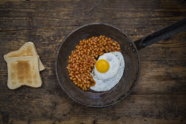 Fried egg and baked beans in frying pan on wood - LVF06123