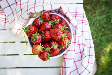 Schale mit Erdbeeren und Küchenhandtuch auf dem Gartentisch - LVF06129