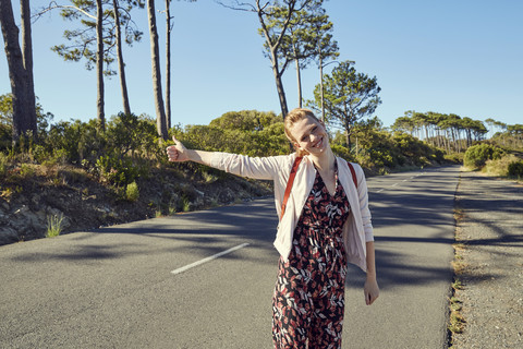 South Africa, Cape Town, Signal Hill, happy young woman hitchhiking on country road stock photo