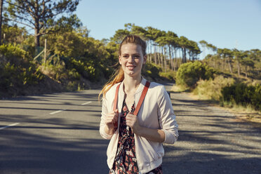 Südafrika, Kapstadt, Signal Hill, lächelnde junge Frau mit Rucksack auf Landstraße - SRYF00524