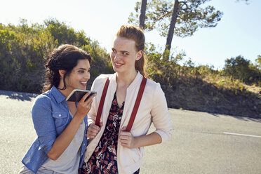 South Africa, Cape Town, Signal Hill, two smiling young women with cell phone on a trip - SRYF00528