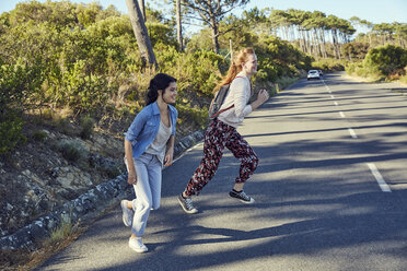 Südafrika, Kapstadt, Signal Hill, zwei glückliche junge Frauen beim Überqueren einer Landstraße - SRYF00534