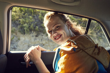Lächelnde junge Frau auf dem Rücksitz eines Autos - SRYF00543