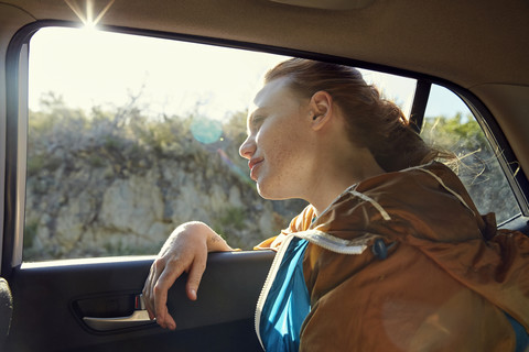 Junge Frau in einem Auto schaut aus dem Fenster, lizenzfreies Stockfoto