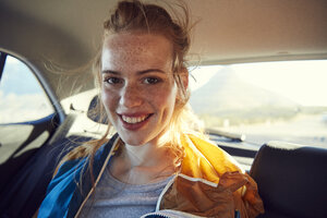 Smiling young woman on the back seat of a car - SRYF00545
