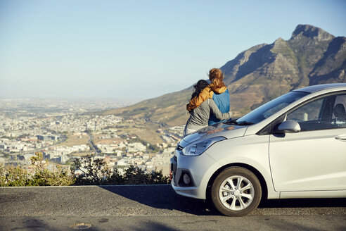 South Africa, Cape Town, Signal Hill, two young women leaning against car overlooking the city - SRYF00549