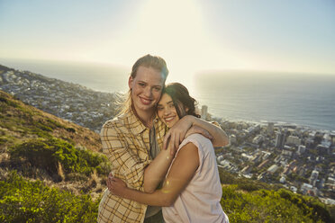 South Africa, Cape Town, Signal Hill, portrait of two young women hugging above the city - SRYF00568