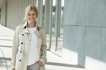 Portrait of smiling blond woman wearing trench coat - CHAF01873