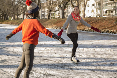 Female friends ice skating on canal - MFF03514