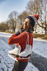 Happy woman on canal carrying ice skates - MFF03520