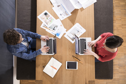 Draufsicht auf einen Mann und eine Frau, die Laptops auf einem Tisch benutzen, lizenzfreies Stockfoto