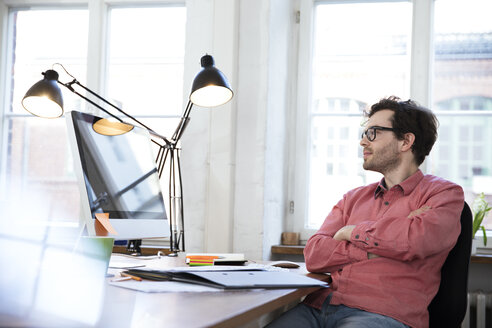 Mann sitzt am Schreibtisch im Büro - FKF02239