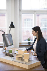 Architektonisches Modell und Frau bei der Arbeit am Schreibtisch im Büro - FKF02241