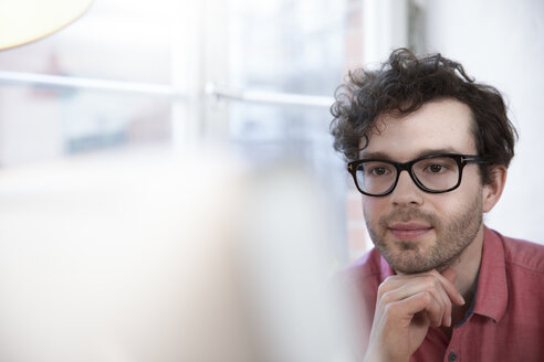 Selbstbewusster Mann im Büro mit Blick auf den Computerbildschirm - FKF02256