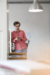 Man using cell phone in office - FKF02257