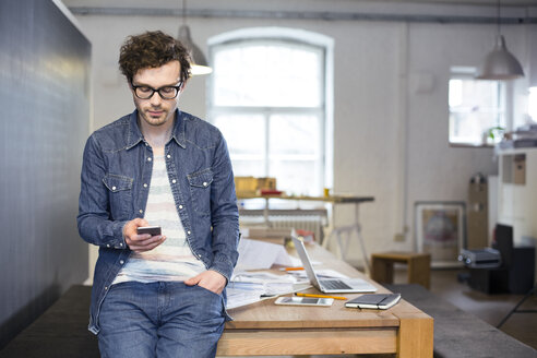 Mann benutzt Mobiltelefon im Büro - FKF02264