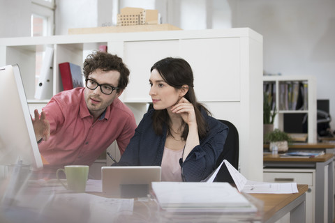 Mann und Frau diskutieren am Schreibtisch im Büro, lizenzfreies Stockfoto