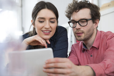 Man and woman looking at tablet in office - FKF02267