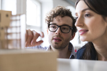 Man and woman discussing architectural model in office - FKF02277