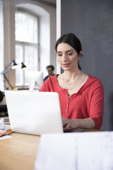 Frau mit Laptop auf Tisch im Büro - FKF02281