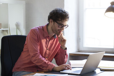 Mann mit Laptop am Schreibtisch im Büro - FKF02301